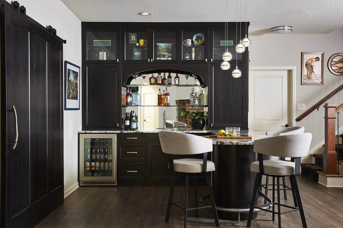 Custom home bar with dark cabinetry and modern seating, designed by MA Peterson in Twin Cities