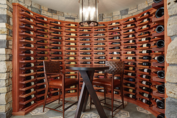 Elegant wine room with curved shelving and stone accents, designed by MA Peterson in Twin Cities