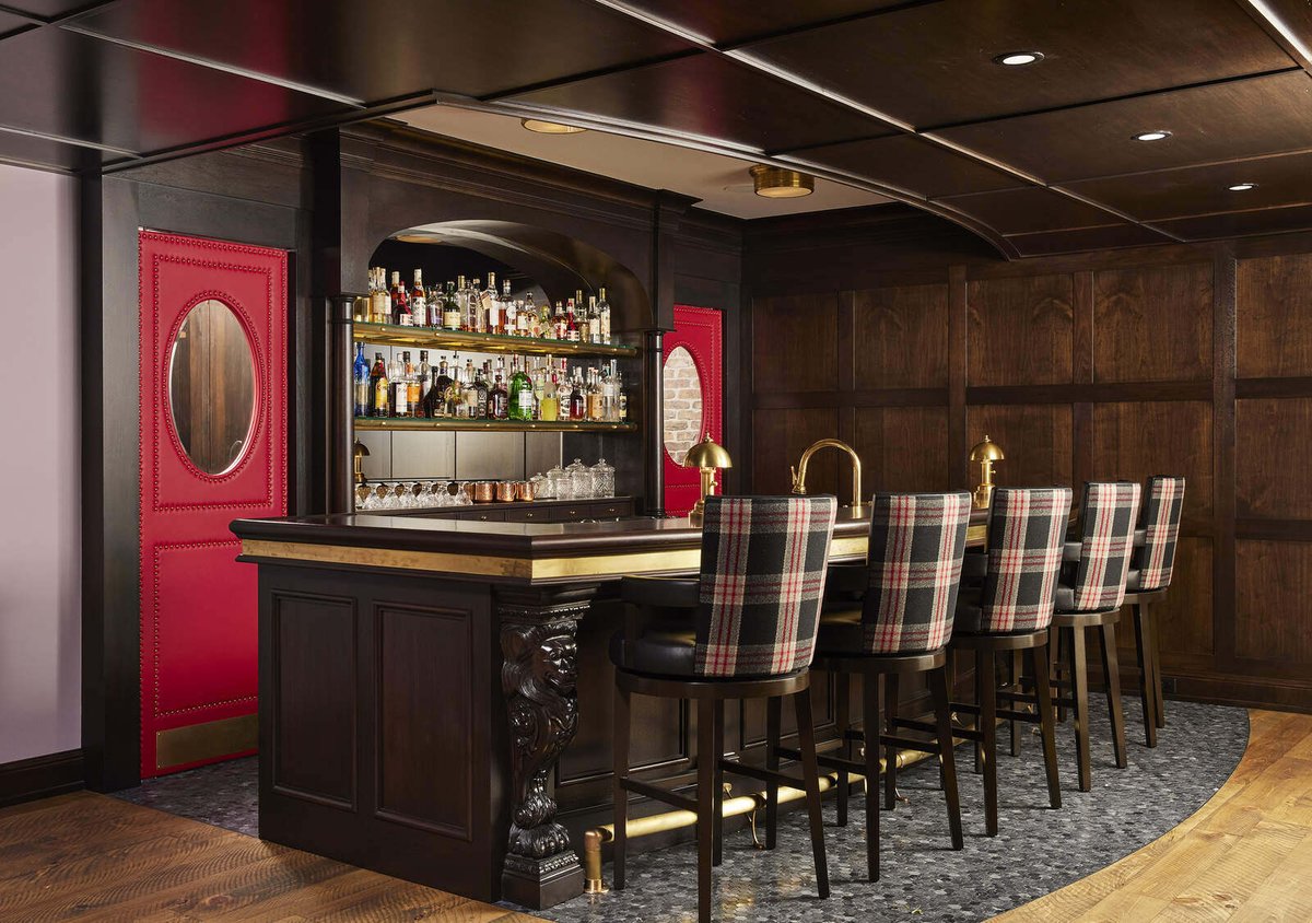 Traditional-style home bar with wood detailing and plaid chairs, crafted by MA Peterson in Twin Cities