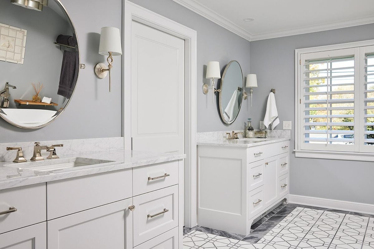 Luxurious white and gray bathroom with double vanities and round mirrors in a Twin Cities home remodeled by MA Peterson