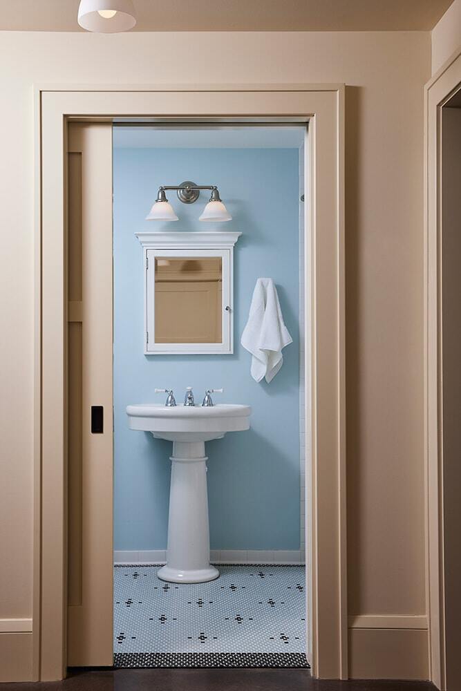 Simple yet elegant powder room featuring a pedestal sink and blue walls, remodeled by MA Peterson in the Twin Cities