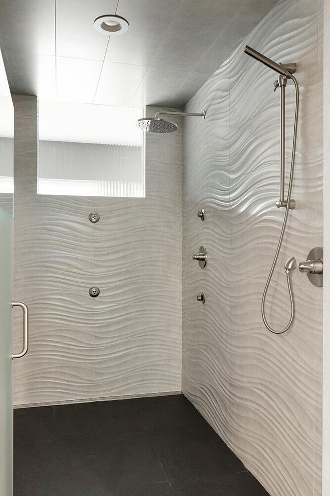 Spacious walk-in shower with wave-patterned tiles by MA Peterson in the Twin Cities