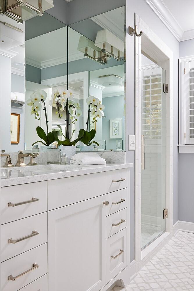 Stylish bathroom remodel with white cabinetry and mirrored walls by MA Peterson in Twin Cities