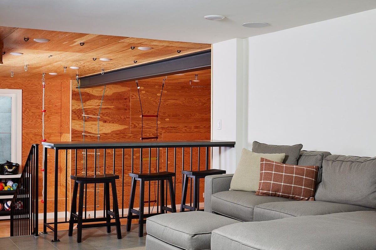 Home playroom with swings and climbing ropes next to a seating area, designed by MA Peterson in the Twin Cities