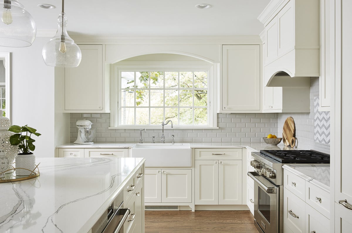 Bright white kitchen with farmhouse sink and marble countertops by MA Peterson in the Twin Cities