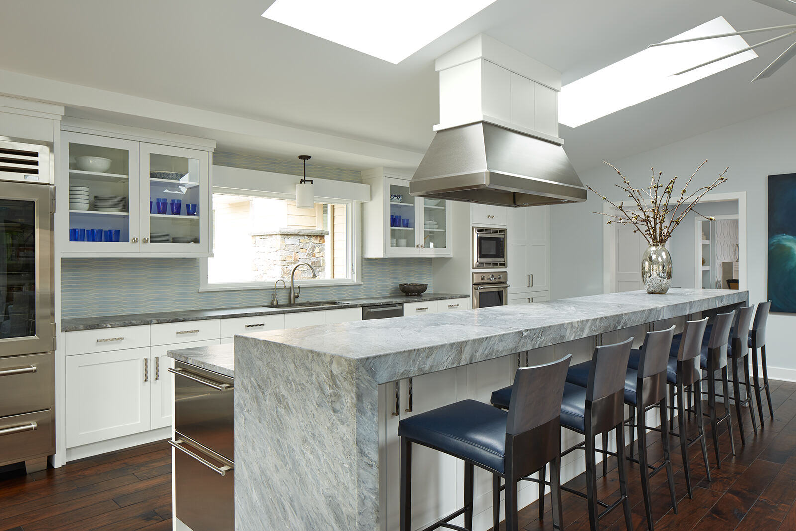 Contemporary kitchen with a long marble island and stainless steel appliances by MA Peterson in the Twin Cities