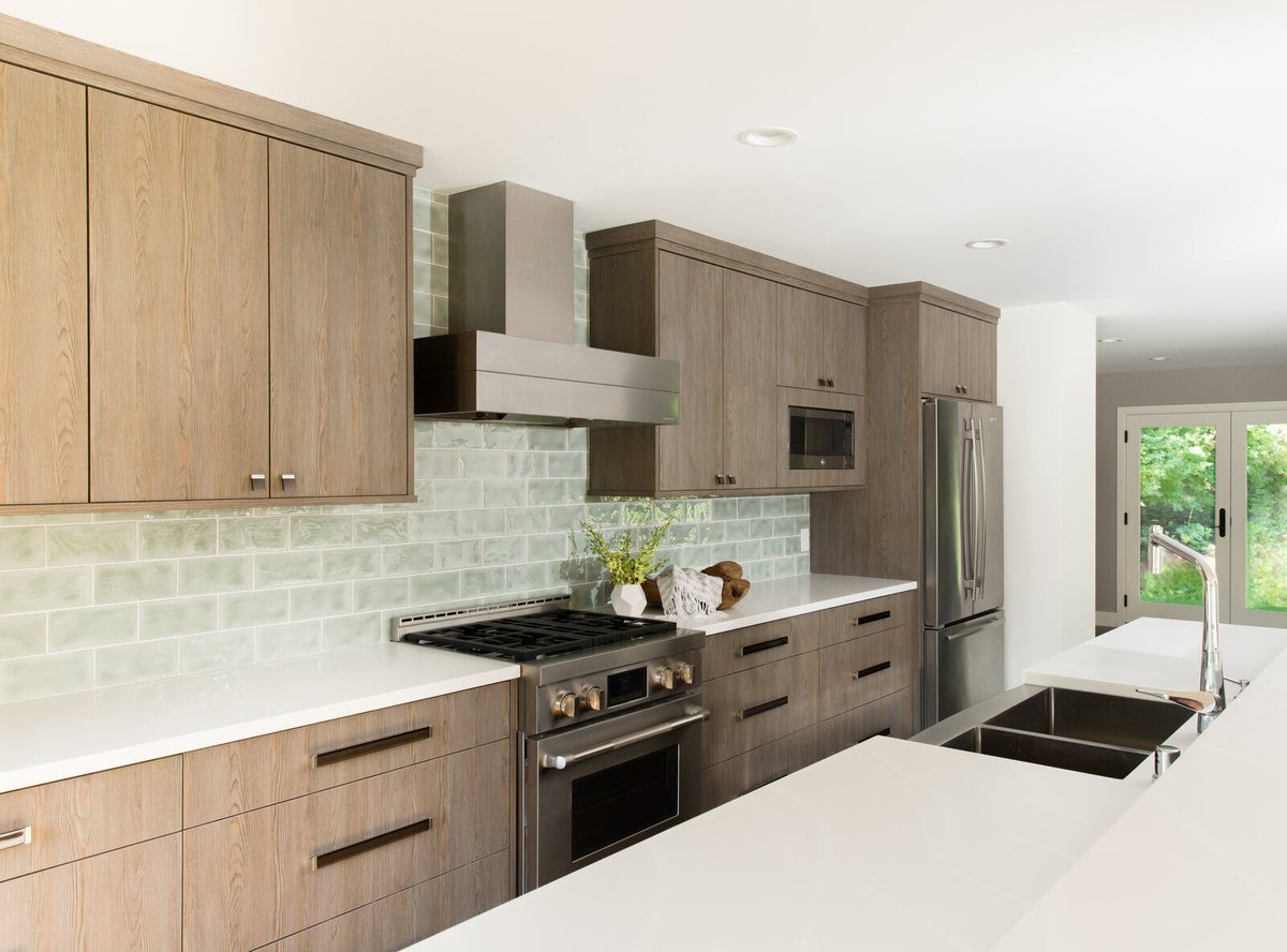 Natural wood cabinets and green tiles in a cozy kitchen remodel by MA Peterson in the Twin Cities