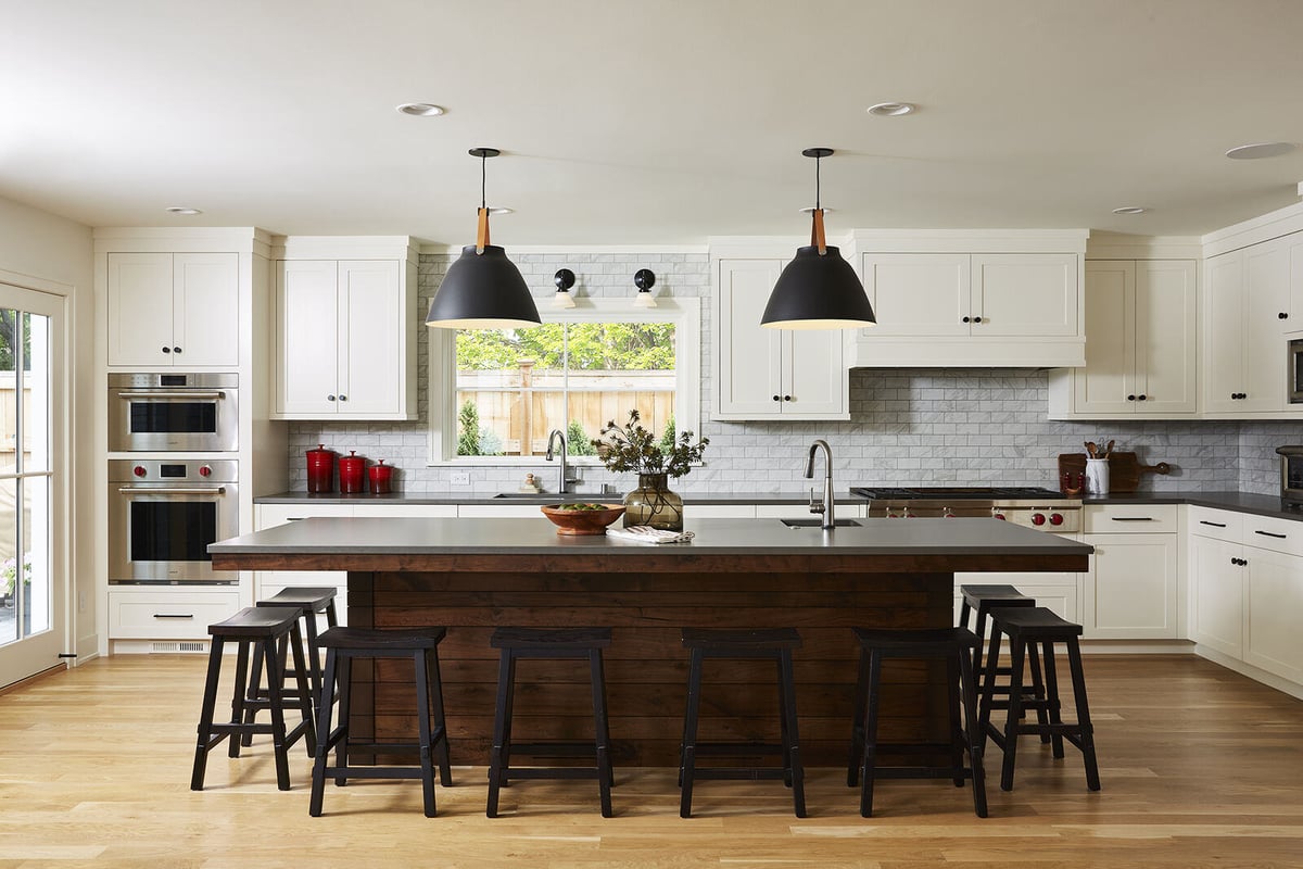 Spacious white kitchen with dark wood island and industrial pendant lights by MA Peterson in the Twin Cities