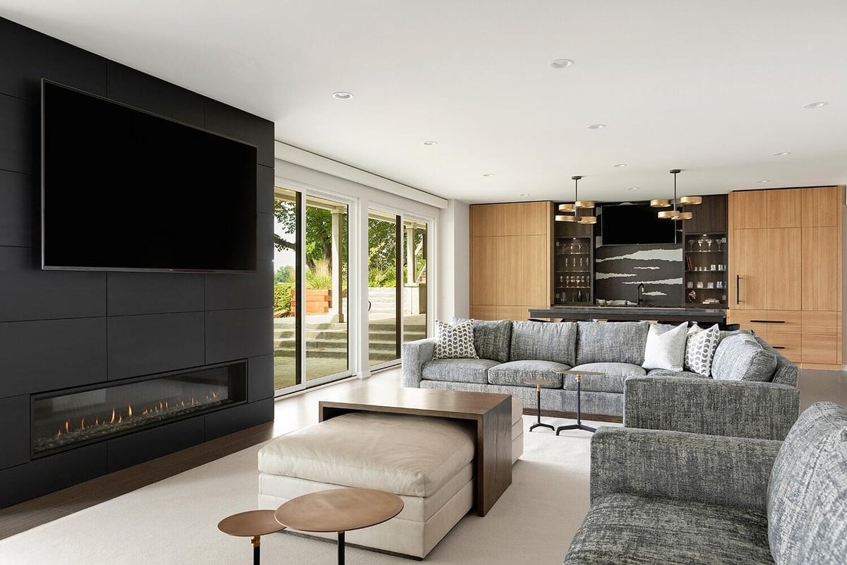 Sleek lower level living room with built-in fireplace and bar by MA Peterson in the Twin Cities