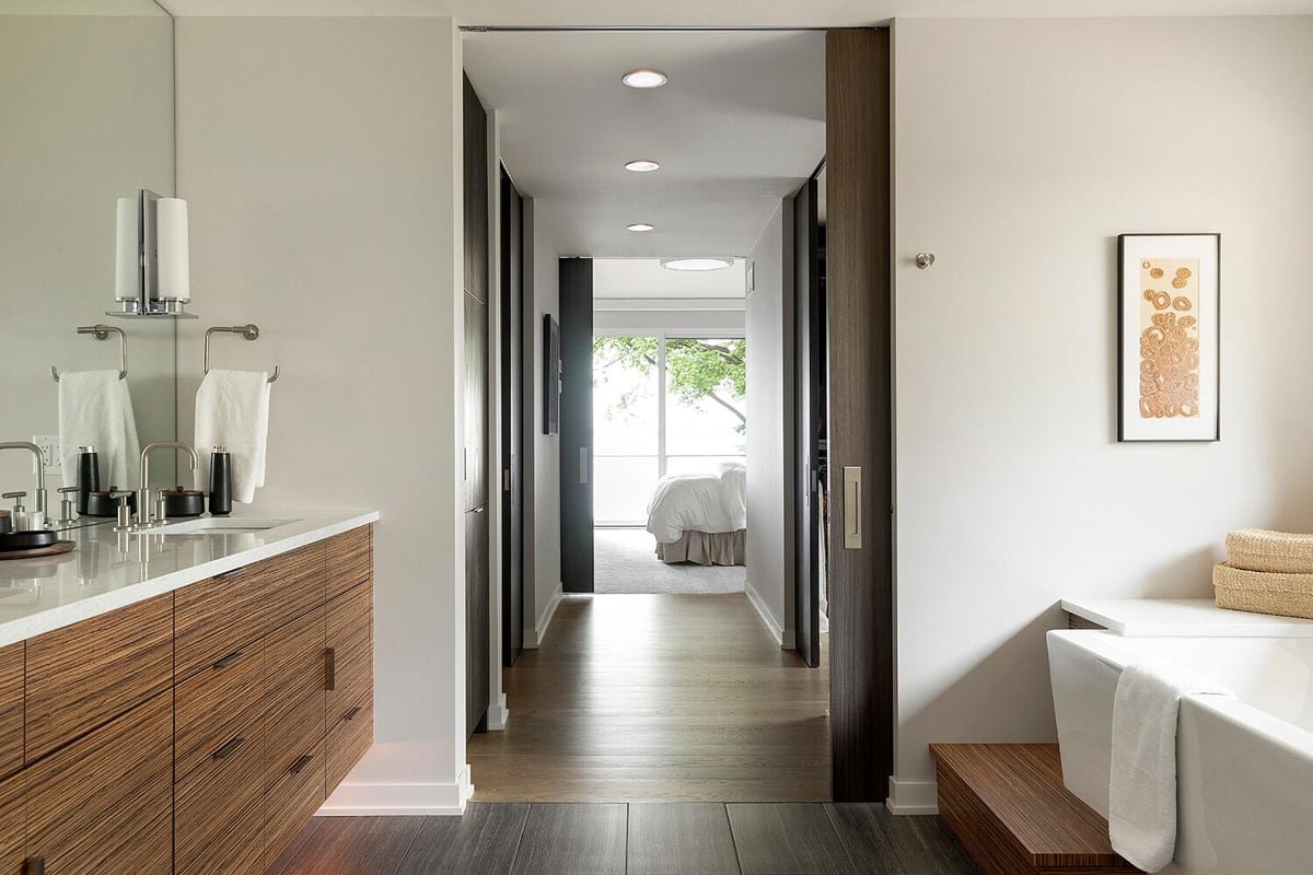 Modern bathroom with wood accents and a spacious hallway view towards a bedroom in a home by MA Peterson, Twin Cities