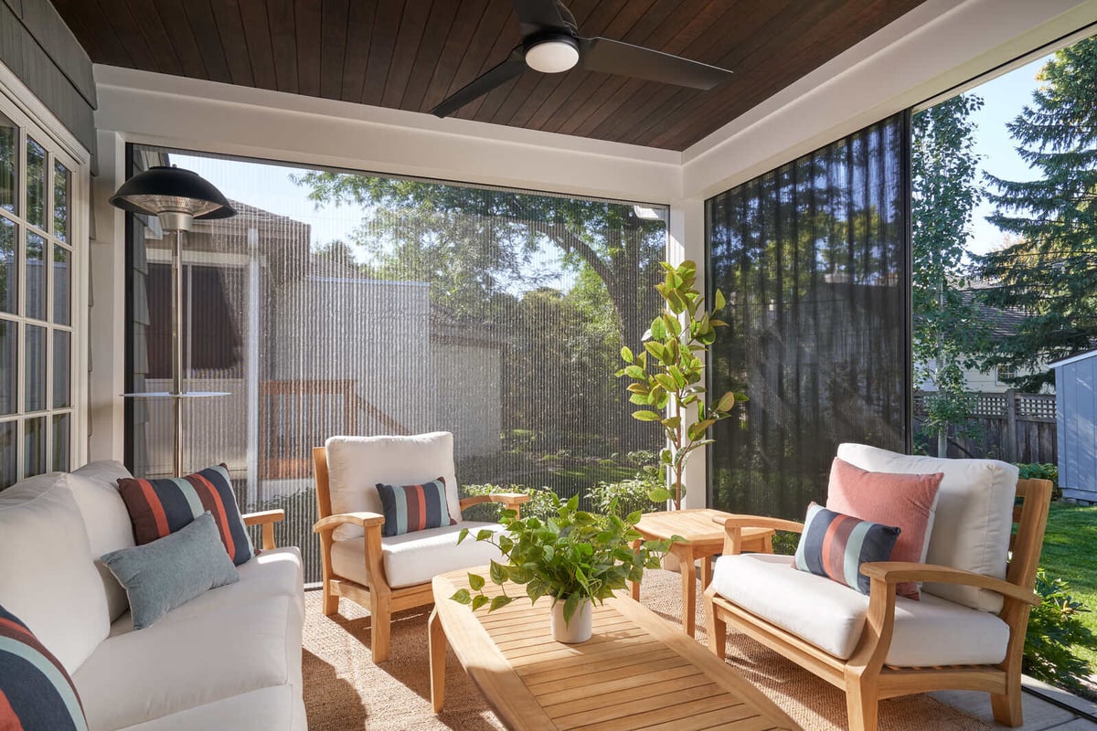 Bright and airy screened-in porch with modern wooden furniture by MA Peterson in the Twin Cities