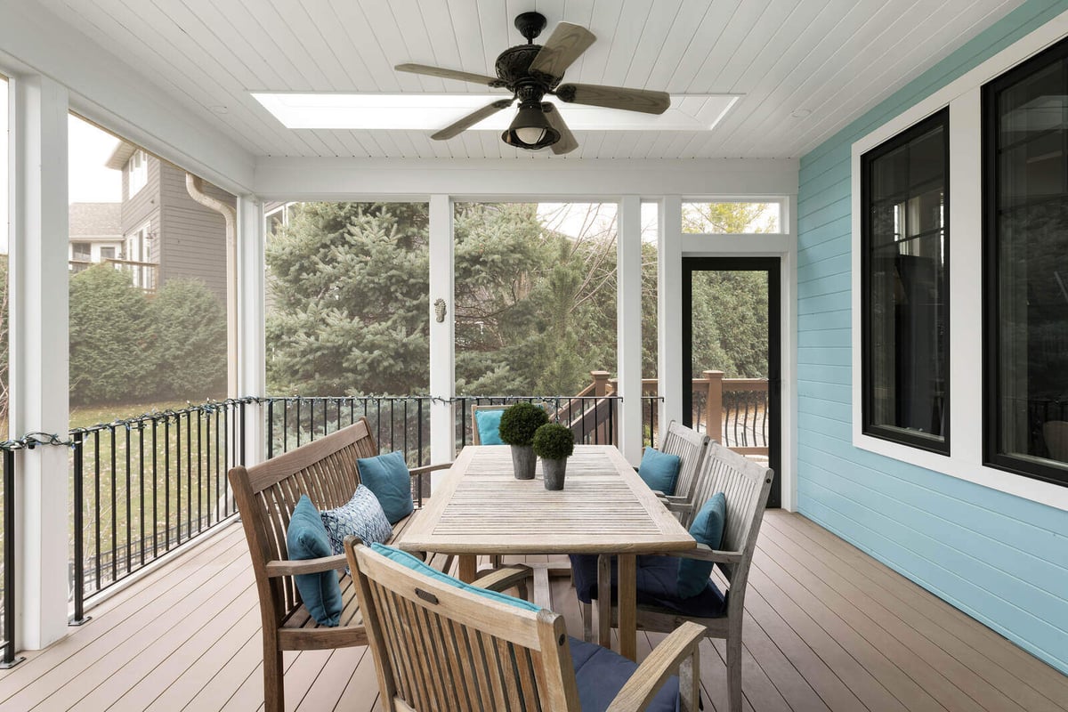 Charming screened porch with wooden dining set, designed by MA Peterson in the Twin Cities