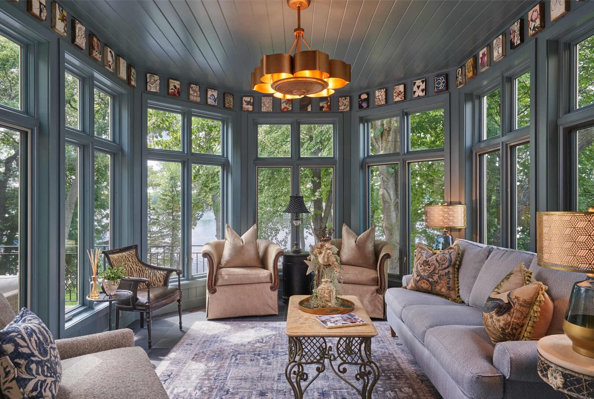 Elegant sunroom with large windows overlooking a lake, designed by MA Peterson in the Twin Cities