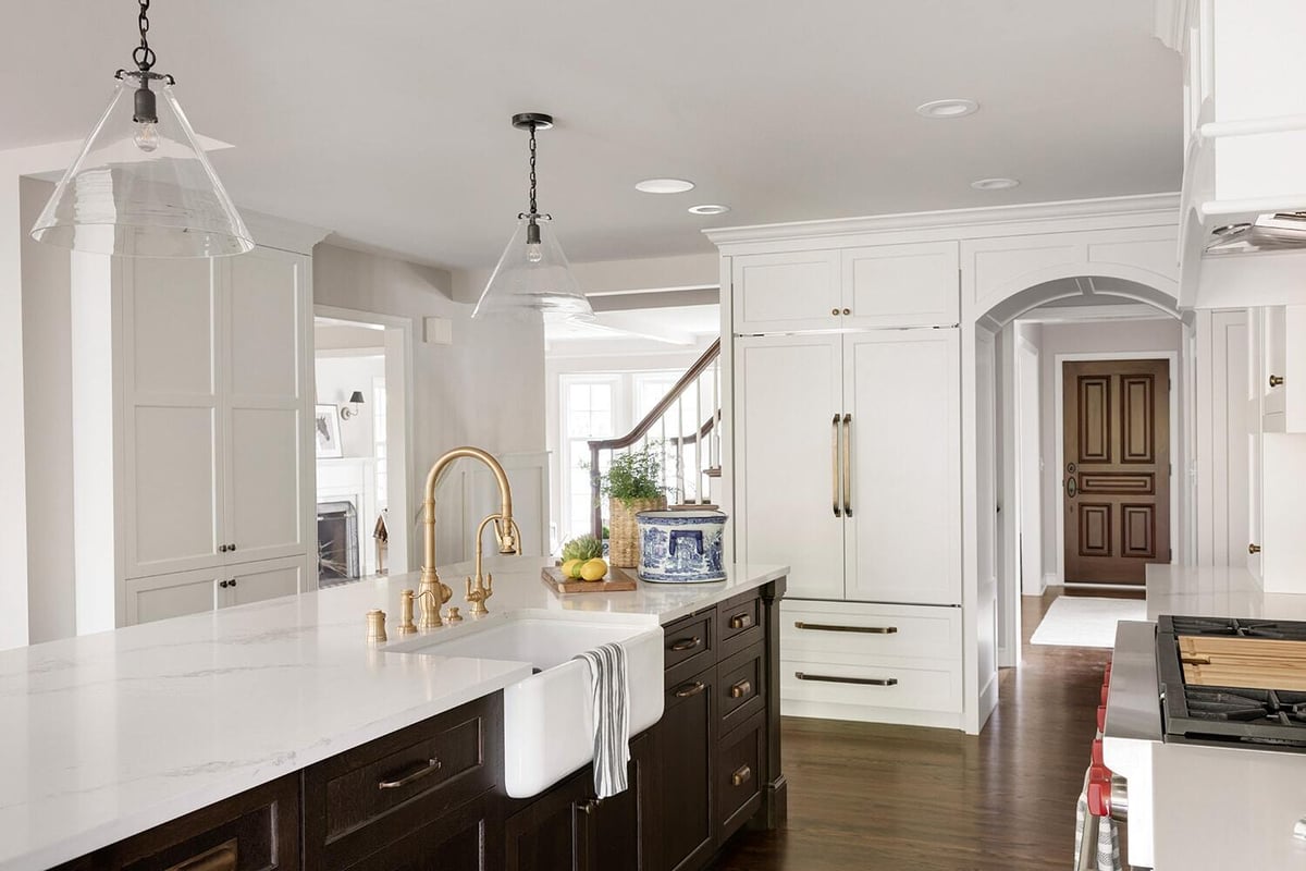 Elegant white kitchen featuring gold fixtures and large island, remodeled by MA Peterson, Twin Cities