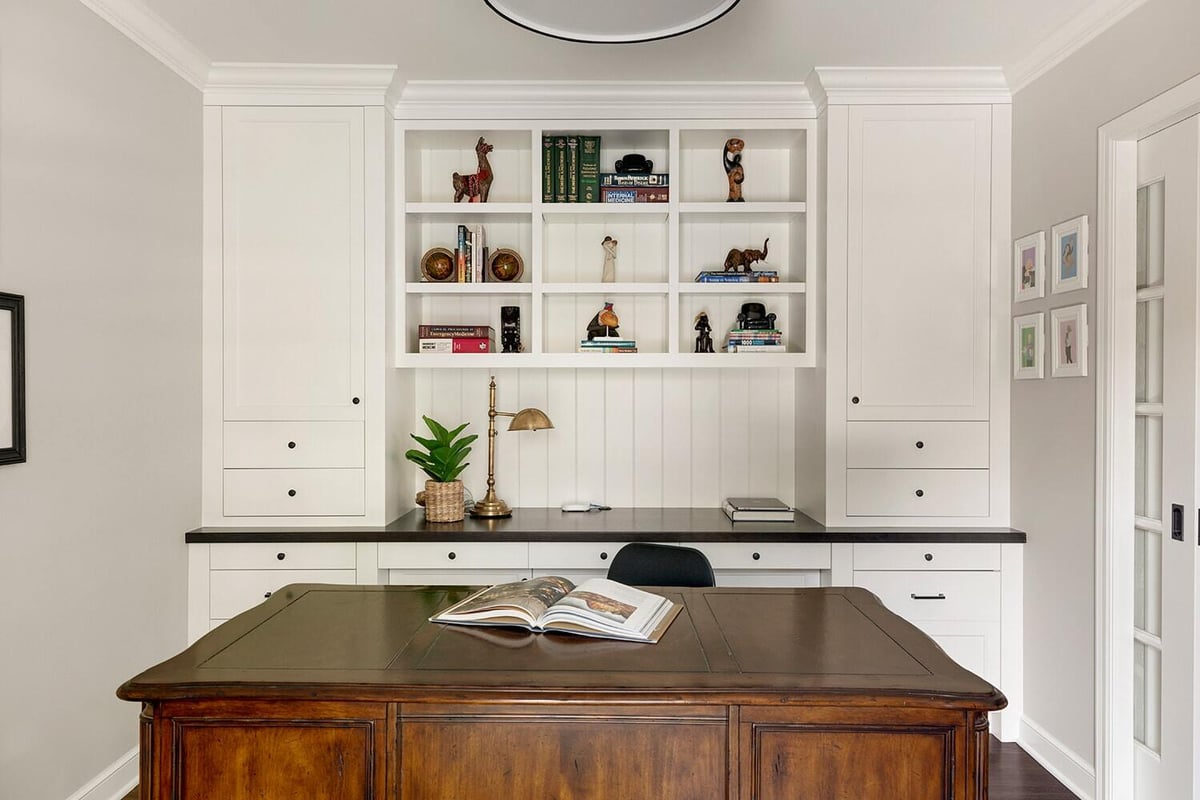 Stylish home office remodel with white cabinetry and a central wooden desk by MA Peterson, Twin Cities