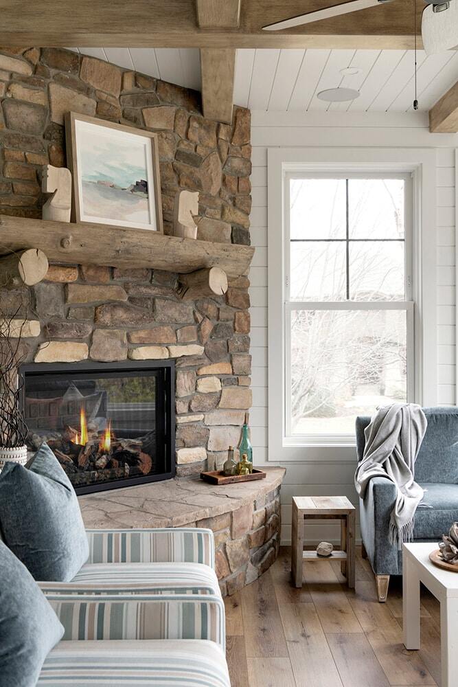 Custom home living room with a stone fireplace and comfortable armchairs in Twin Cities by MA Peterson