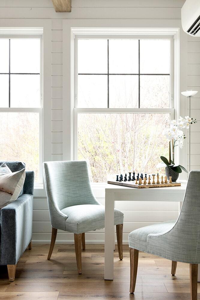 Dining area with light blue chairs and a chessboard by the window in a custom home by MA Peterson, Twin Cities