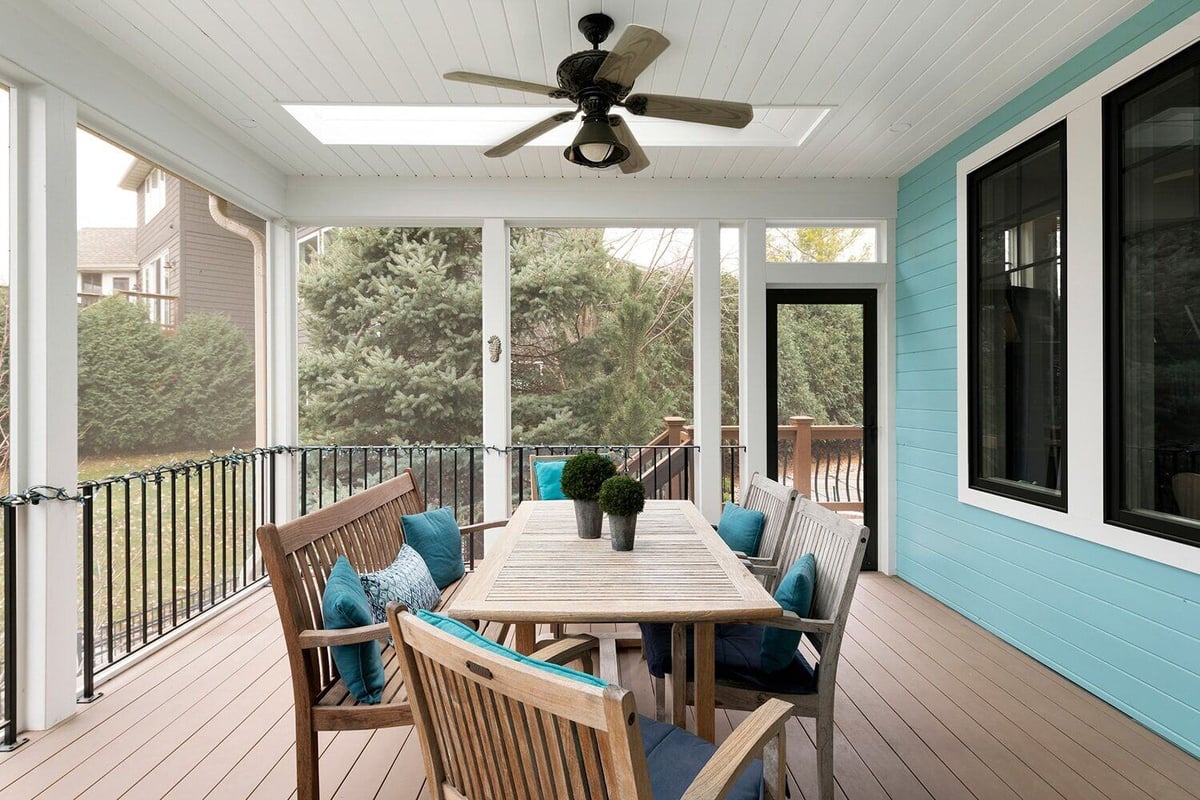 Enclosed porch with dining table and ceiling fan in a Twin Cities custom home by MA Peterson