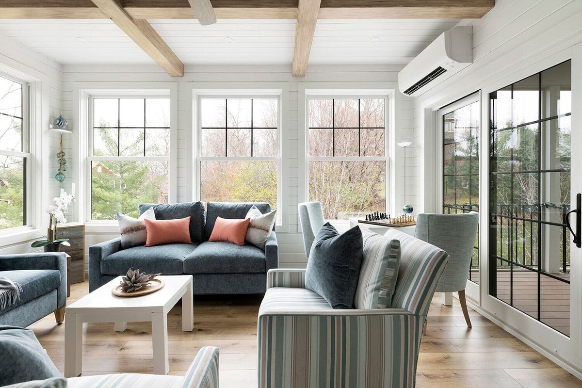 Light-filled sunroom featuring blue couches and scenic views in a Twin Cities custom home by MA Peterson