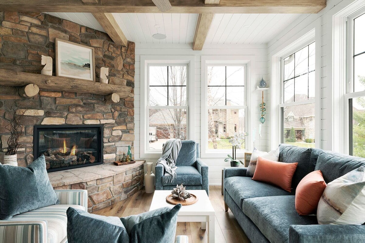 Sunlit living area featuring blue couches and a rustic stone fireplace in a Twin Cities custom home by MA Peterson