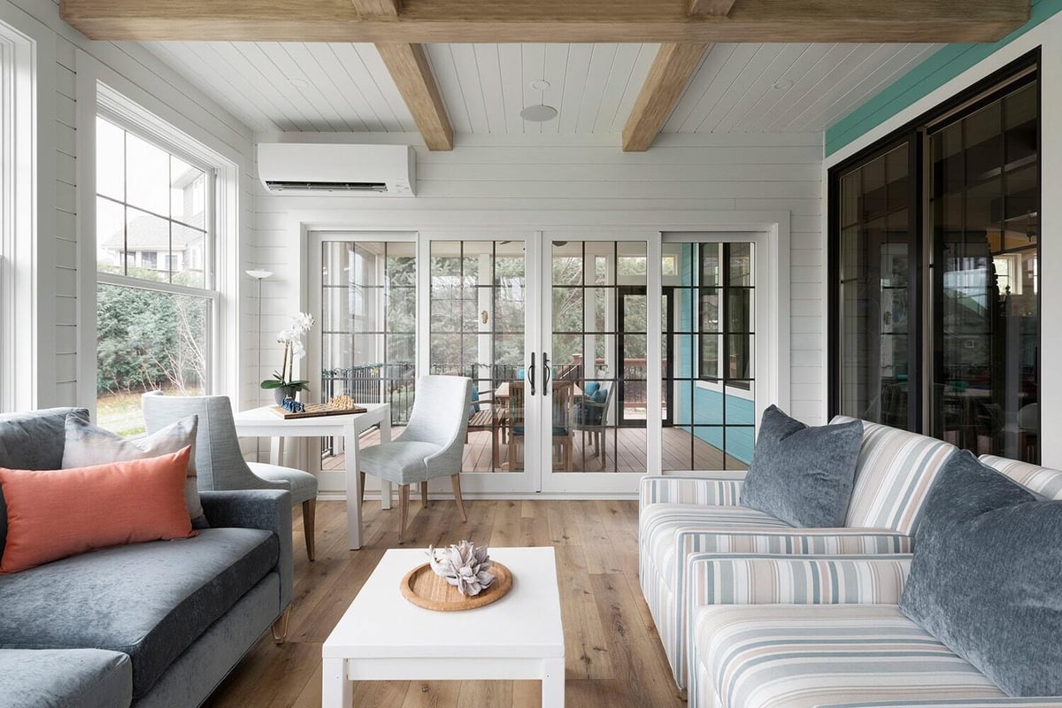 Sunroom with blue and striped seating and large windows in a Twin Cities custom home by MA Peterson