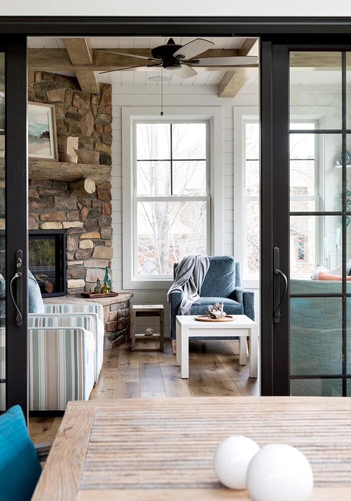 View of living room through glass doors with a stone fireplace in a Twin Cities custom home by MA Peterson