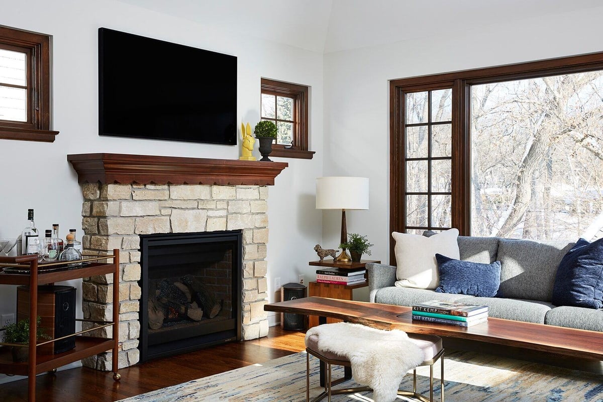 Cozy living room featuring a stone fireplace and large windows, remodeled by MA Peterson in the Twin Cities