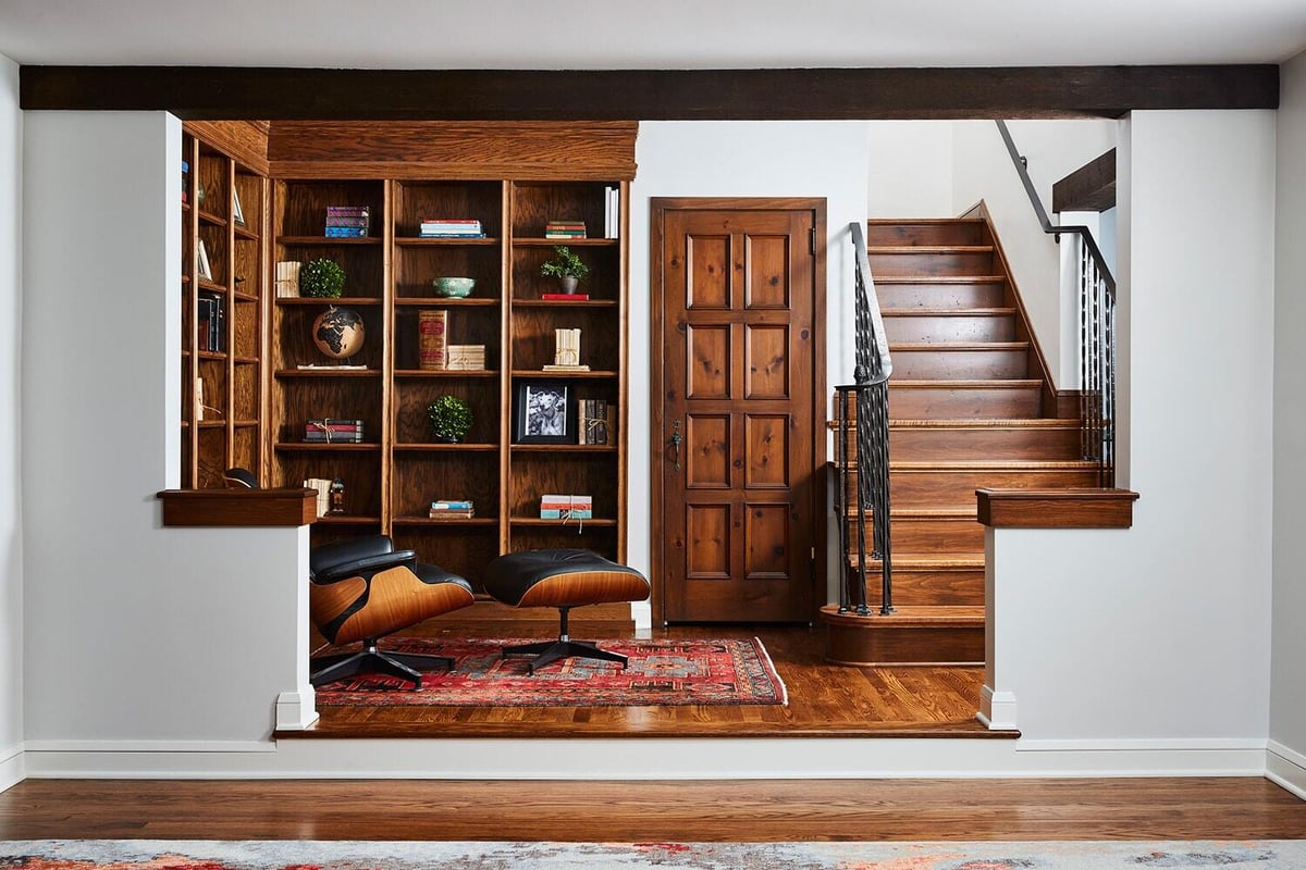 Home library with wooden shelving and staircase in a remodel by MA Peterson in the Twin Cities