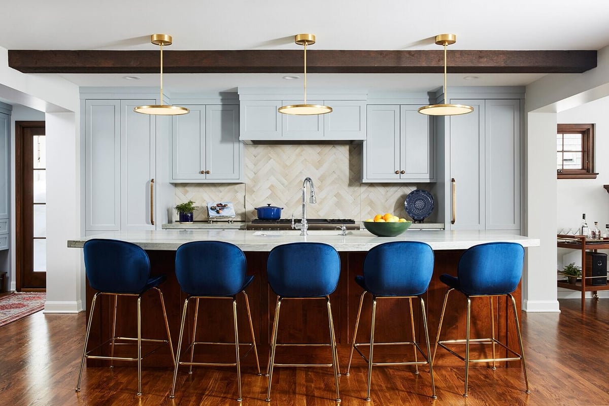 Kitchen island with blue bar stools and modern light fixtures in a home remodeled by MA Peterson in the Twin Cities