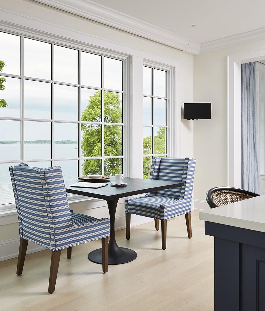 Coastal Chic dining nook featuring striped chairs and scenic lake view, designed by MA Peterson in the Twin Cities