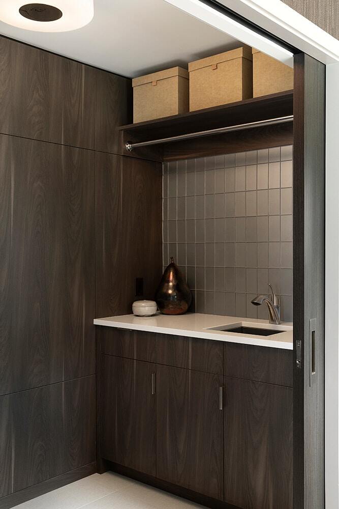 Compact laundry area with dark wooden cabinetry, designed by MA Peterson in Twin Cities