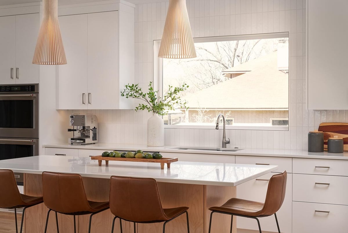 Bright kitchen with island and large window in Crafting Warmth in Modern home, remodeled by MA Peterson