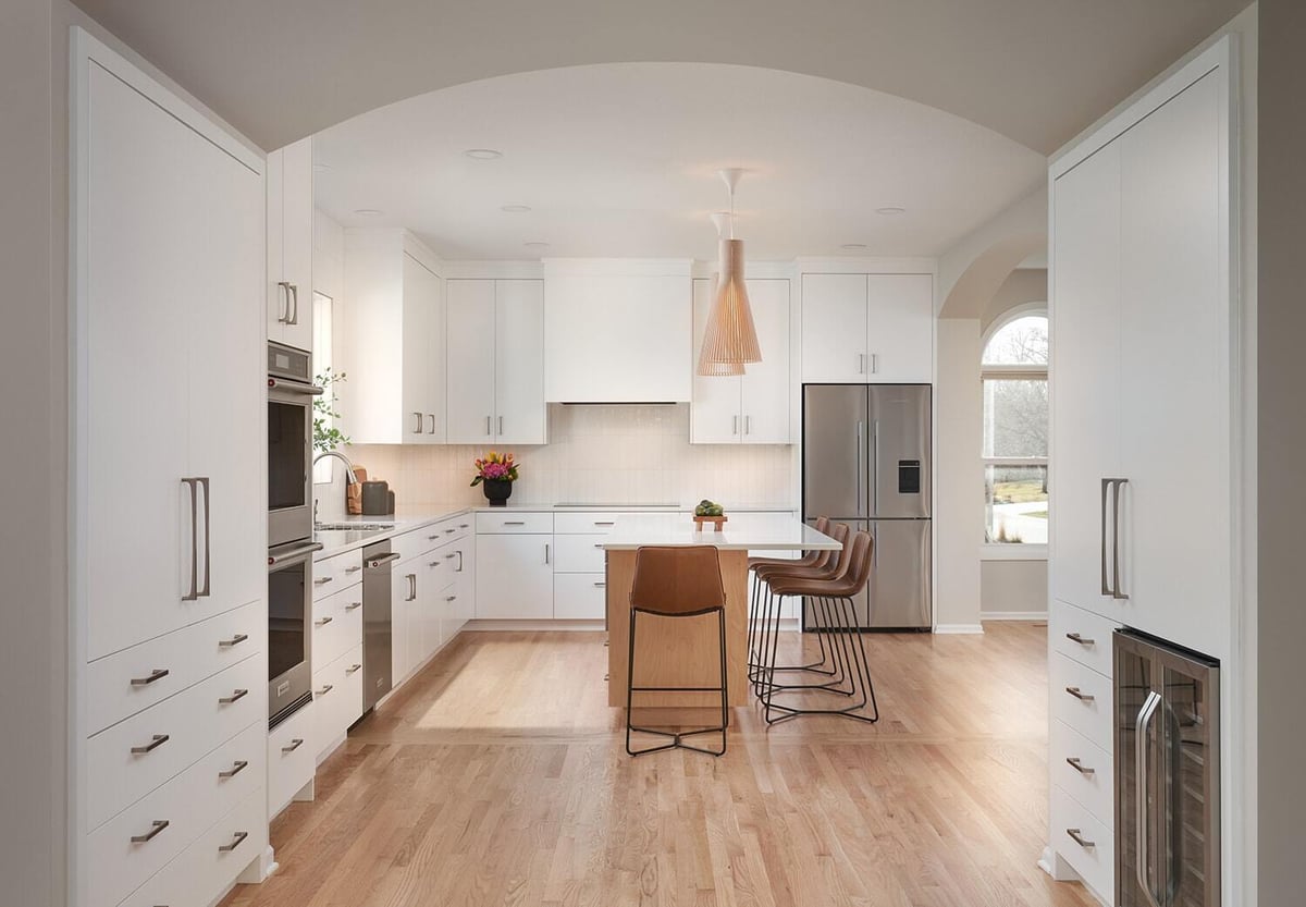 Crafting Warmth in Modern kitchen featuring a white island and seating, designed by MA Peterson in Twin Cities