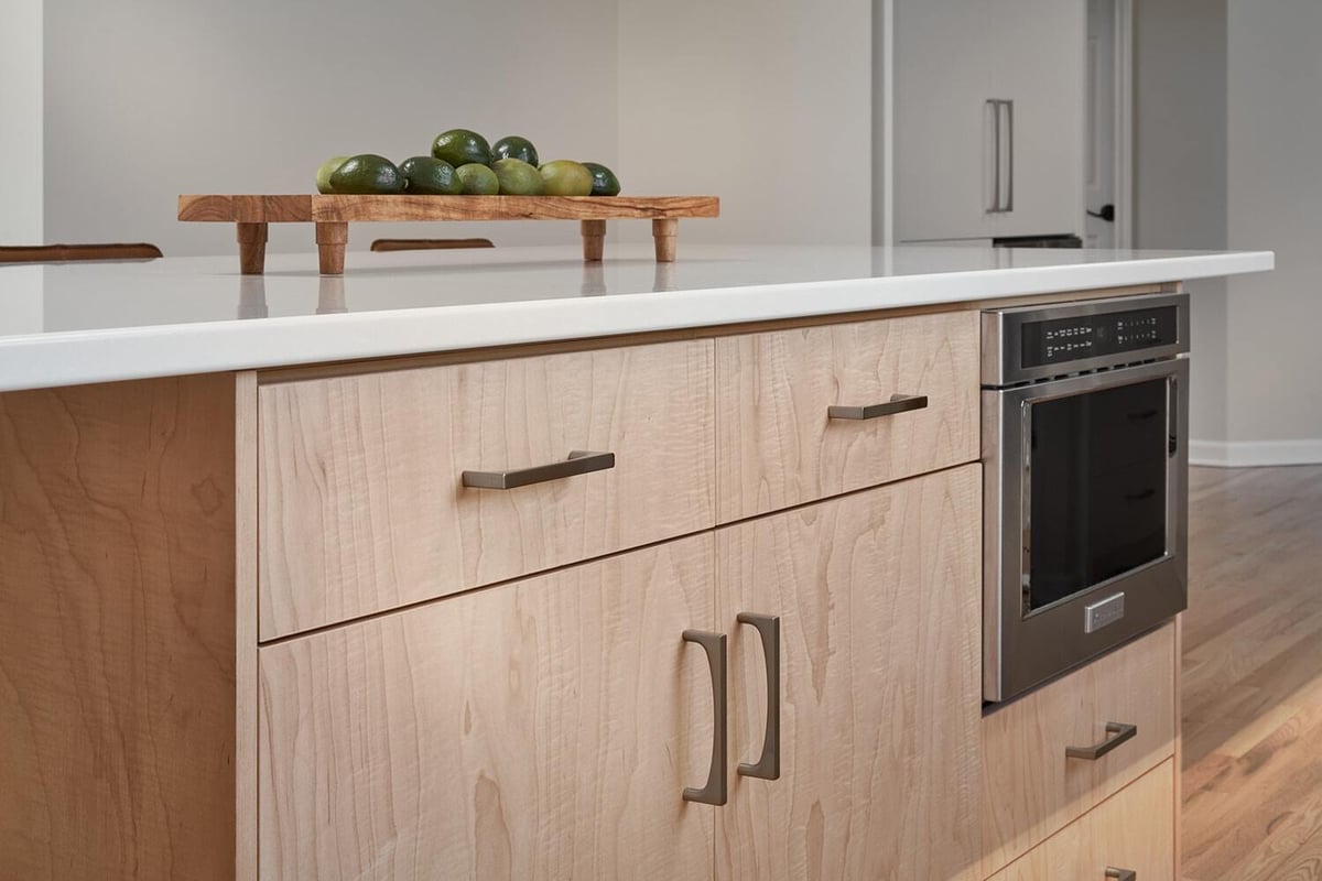 Kitchen island with modern storage and appliances in Crafting Warmth in Modern home by MA Peterson