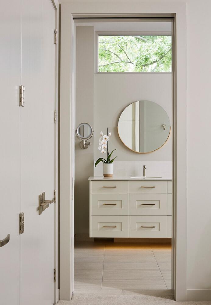 Bathroom with sleek vanity and round mirror in Lake Cornelia home, remodeled by MA Peterson in Twin Cities