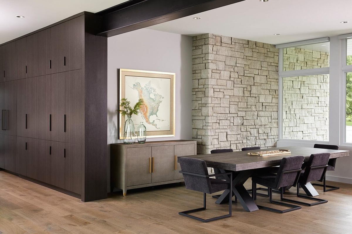 Modern dining area with stone accent wall and dark cabinetry in Lake Cornelia home, designed by MA Peterson in Twin Cities