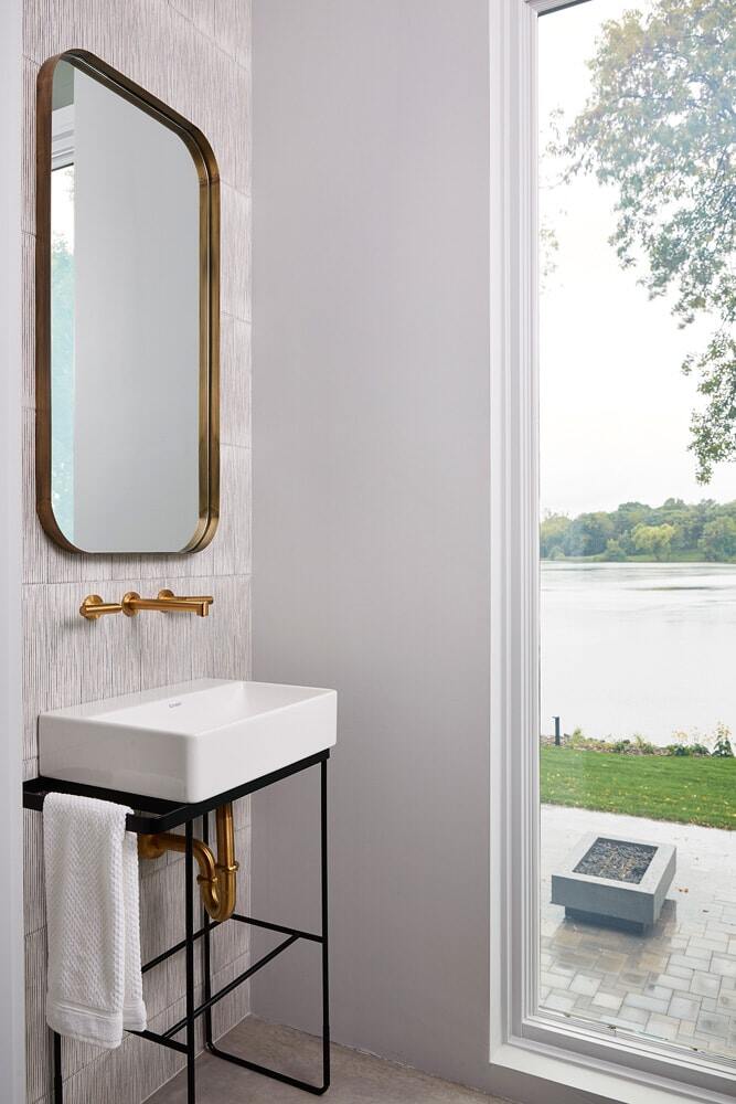 Small bathroom with brass fixtures and lake view in Lake Cornelia remodel by MA Peterson, Twin Cities