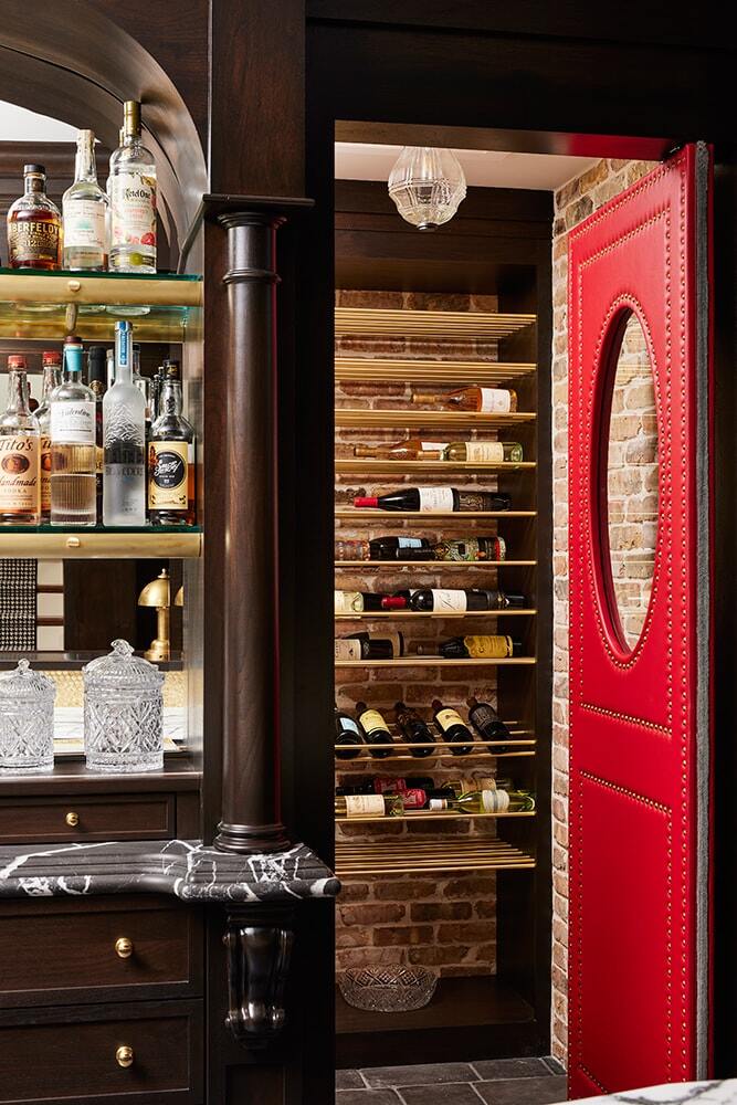 Classic bar with dark wood, arched opening, and red door leading to wine cellar by MA Peterson in Twin Cities