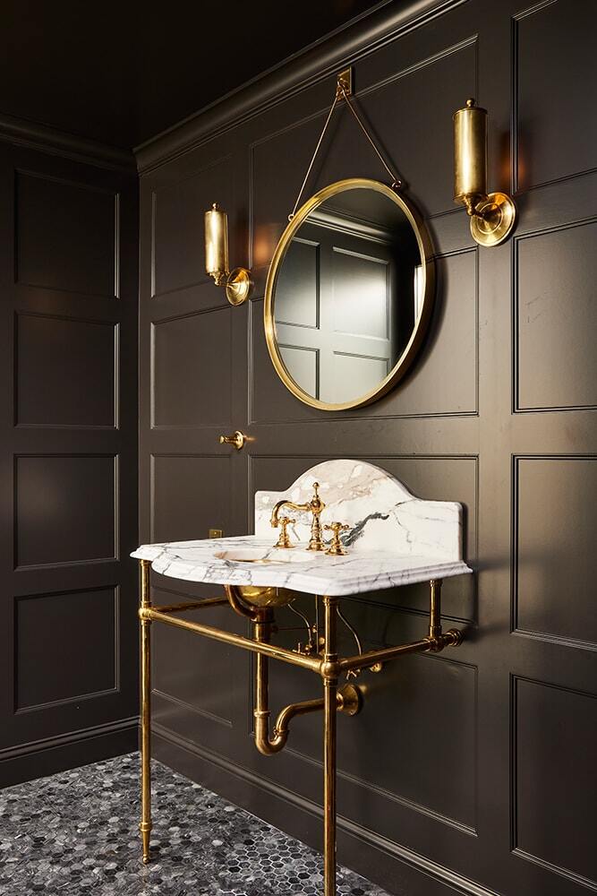 Luxurious bathroom with dark paneled walls and gold-accented marble sink by MA Peterson in Twin Cities