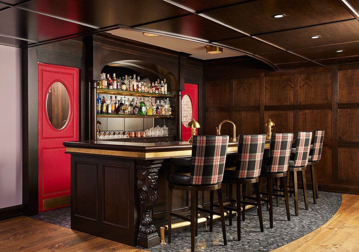 Luxurious pub-inspired home bar with a red door and dark wood accents by MA Peterson in Twin Cities