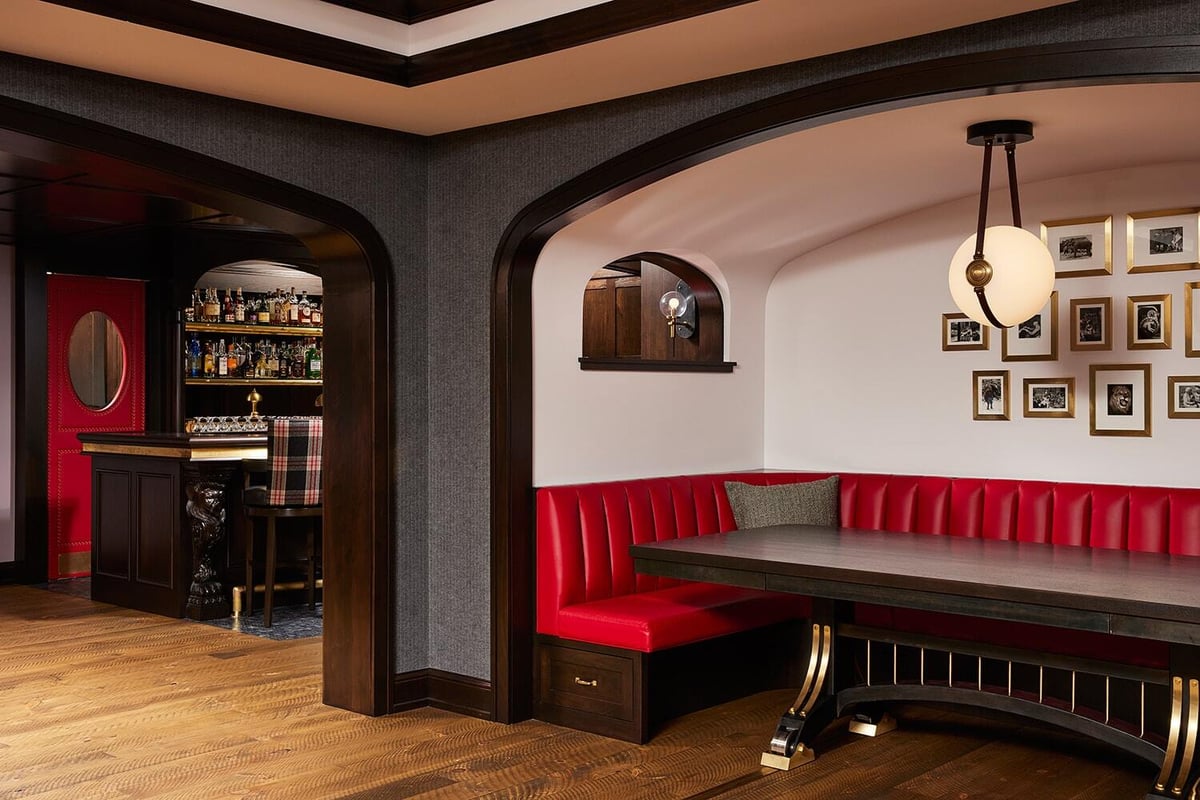 Vintage pub seating area with red booth, dark wood table, and classic decor by MA Peterson in Twin Cities