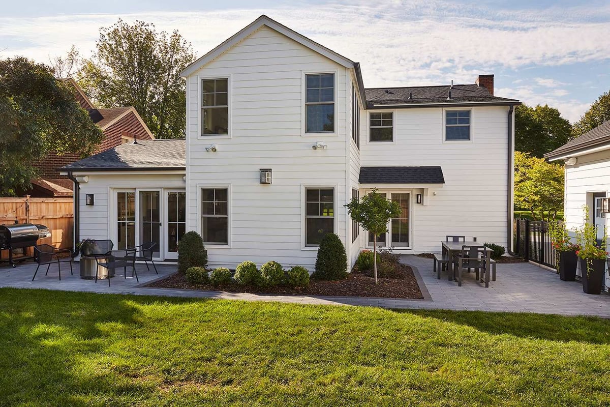 Backyard view of remodeled white house with patio area in Twin Cities by MA Peterson