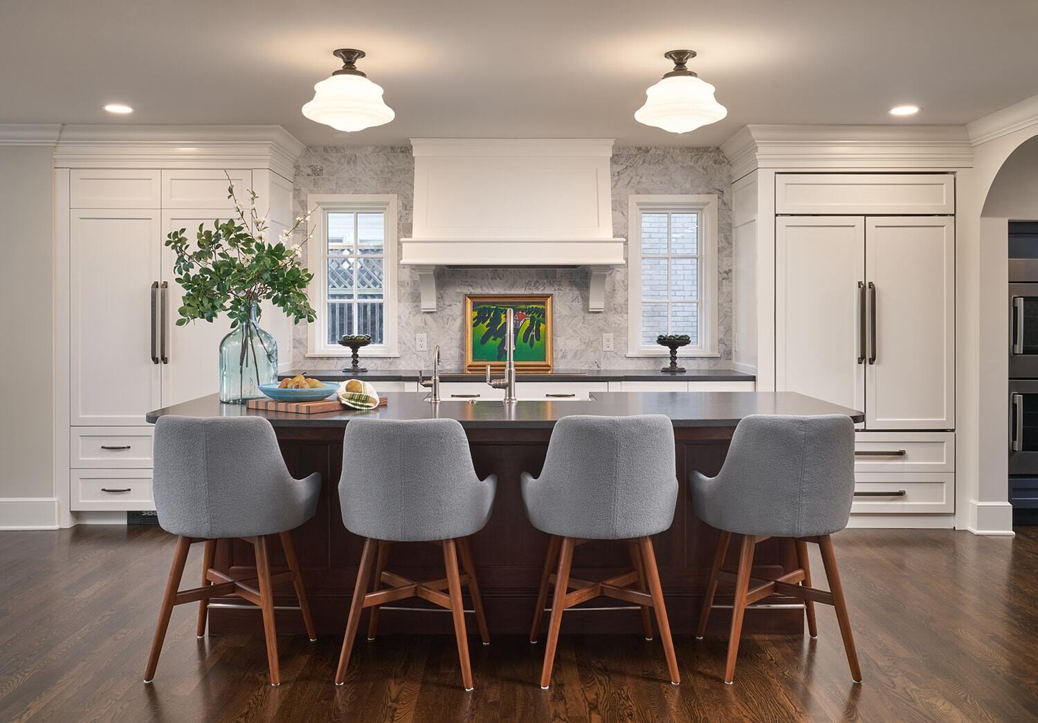 Modern kitchen with grey chairs and a marble backsplash with emphasis on style and decor by MA Peterson in Twin Cities