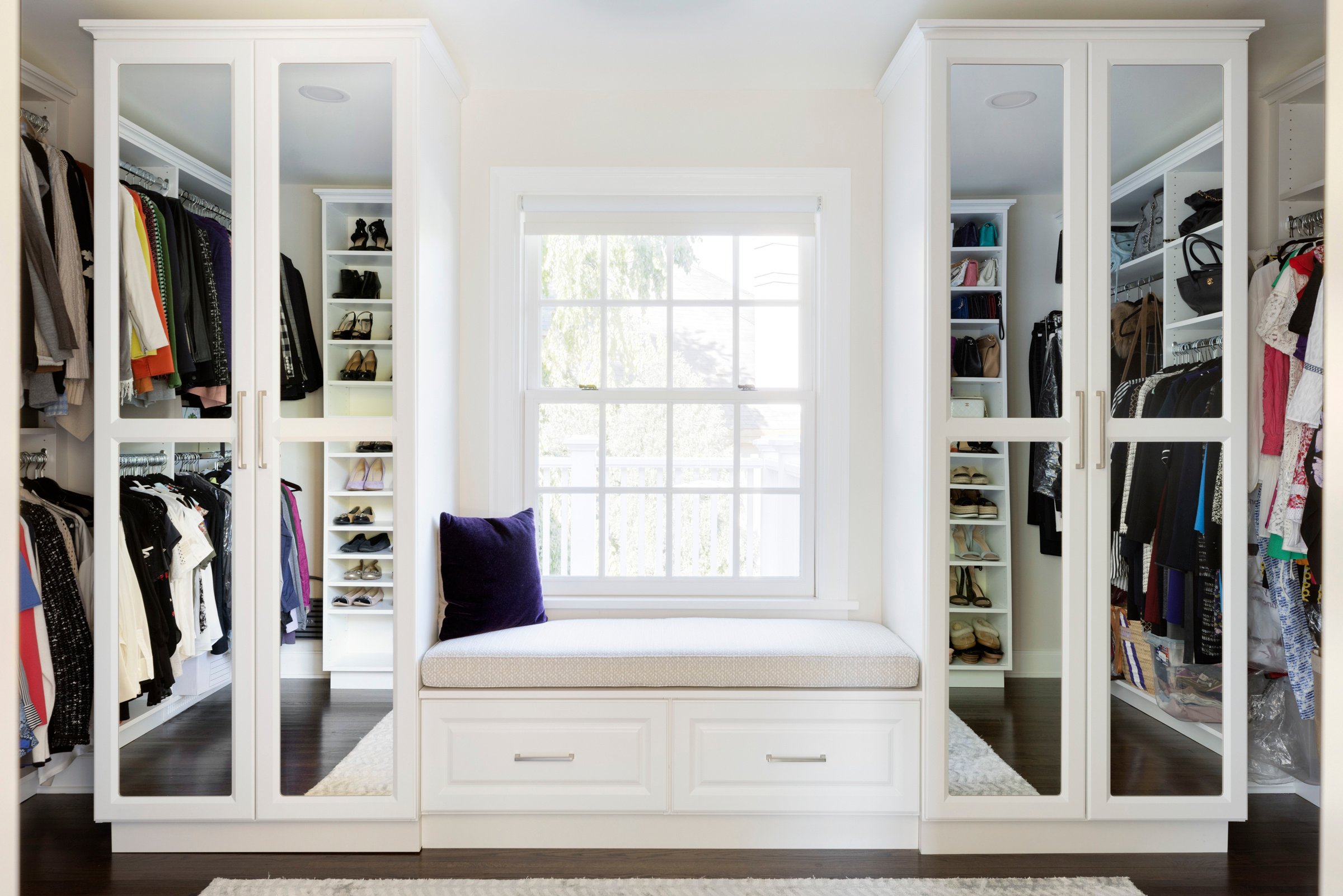 Custom walk-in closet in primary suite with boutique-style lighting and built-in bench.